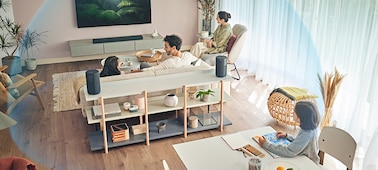 Una familia sentada en diferentes zonas de la sala viendo TV, rodeada de una cúpula azul que representa el sonido espacial 360