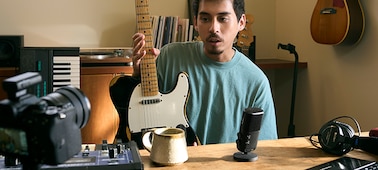 Imagen de uso de un hombre con una guitarra y que habla por el micrófono cercano mientras mira a la cámara con el receptor conectado