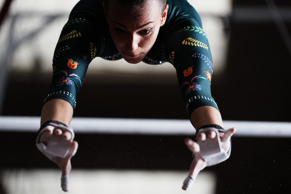 Imagen de ejemplo de una gimnasta en pleno balanceo entre barras asimétricas, con los brazos extendidos